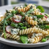 A vibrant spring pasta salad featuring tender pasta, blanched asparagus, sugar snap peas, and radishes, all coated in zesty lemon vinaigrette.