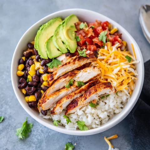 Spicy Chicken Burrito Bowl topped with zesty salsa, cheese, and cilantro, served with fresh lime wedges.  