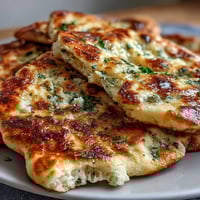 Freshly baked The Best Easy Garlic Naan Bread with golden brown bubbles and melted garlic butter brushed on top.