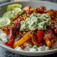 Golden-brown Sheet Pan Chicken Tinga Bowl with fluffy white rice, charred peppers, and a chunky avocado salsa topping.